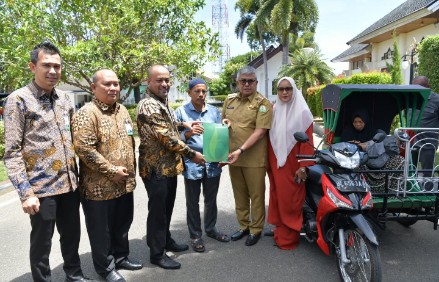 Pj Gubernur Aceh Bustami bersama istri Mellani Subarni, didampingi Plt Direktur Utama Bank Aceh Syariah, Fadhil Ilyas, menyerahkan bantuan satu unit becak untuk Abdul Azis untuk operasional pengobatan anaknya Muhammad Ramadhan yang menderita sakit lumpuh sejak lahir, di halaman Pendopo Gubernur, Senin, (10/6/2024).