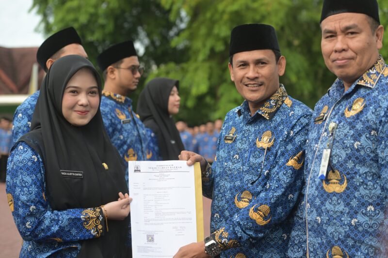 Banda Aceh - Asisten II Sekda Aceh, Zulkifli, mewakili Gubernur Aceh, menyerahkan Surat Keputusan (SK) Gubernur tentang Pengangkatan 618 Calon Aparatur Sipil Negara (CASN) Pemerintah Aceh Tahun 2024. Penyerahan SK dilakukan dalam sebuah upacara yang berlangsung di Halaman Kantor Gubernur Aceh, Selasa 17 Juni 2025.