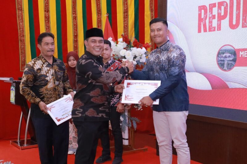 Bupati Aceh Besar, H Muharram Idris menyerahkan piagam kepada perugas pengibar bendera pada malam resepsi dan syukuran memperingati Hari Ulang Tahun (HUT) ke-80 Kemerdekaan Republik Indonesia yang digelar di Meuligoe Bupati Aceh Besar, Kota Jantho, Minggu (17/8/2025). FOTO/MC ACEH BESAR