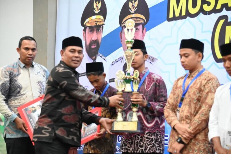 Bupati Aceh Besar H. Muharram Idris menyerahkan piala kepada para juara pada penutupan MQK ke-IV Tingkat Provinsi Aceh Tahun 2025 di Hotel Grand Aceh Syariah, Lamdom, Banda Aceh, Kamis (21/8/2025) malam. FOTO/MC ACEH BESAR