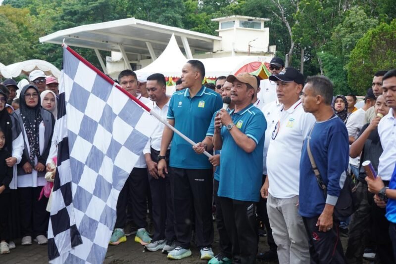 Wakil Bupati Aceh Besar Drs. H. Syukri A Jalil mengangkat bendera start saat menglepaskan peserta jalan sehat keluarga di lapangan Bungoeng jeumpa, Kota Jantho, Minggu (23/11/2025) pagi. FOTO/MC ACEH BESAR