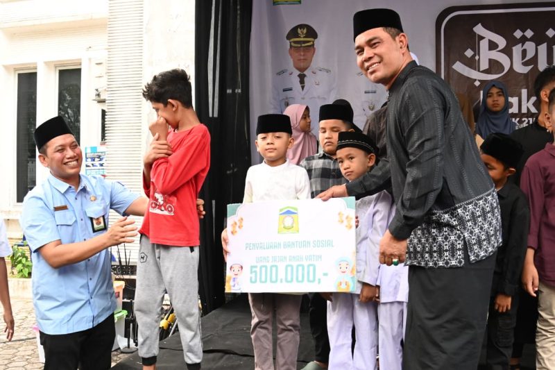 Bupati Aceh Besar, H Muharram Idris menyerahkan Santunan kepada Anak Yatim di Halaman Dekranasda Aceh Besar, Gampong Gani, Kecamatan Ingin Jaya, Aceh Besar, Selasa (10/03/2026). FOTO/MC ACEH BESAR