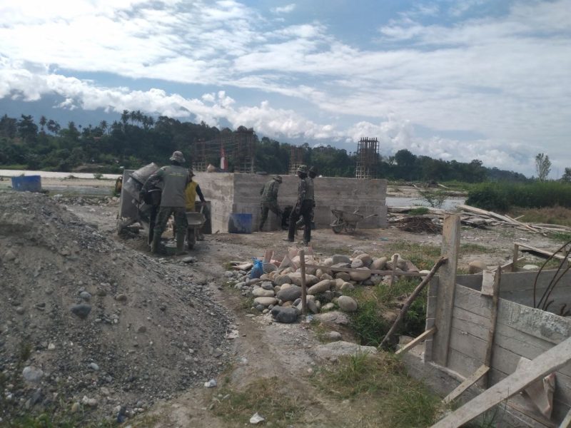 personel Babinsa jajaran Kodim 0108/Aceh Tenggara bersama masyarakat melaksanakan pemasangan besi penahan pondasi serta persiapan pemasangan tiang jembatan guna memperkuat struktur konstruksi dan memastikan keamanan fasilitas tersebut, Kamis (28/05/2026).
