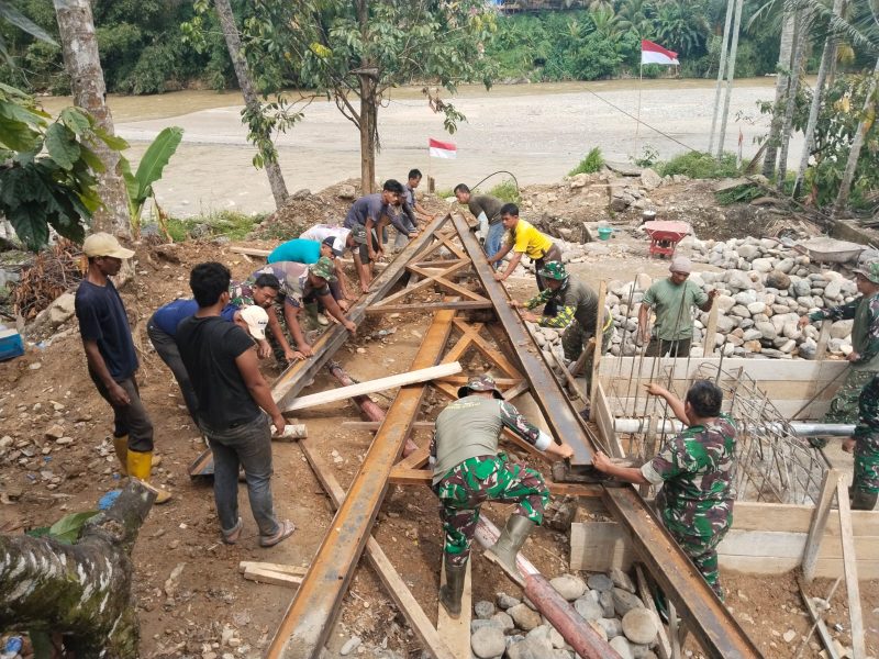 Babinsa jajaran Kodim 0108/Aceh Tenggara bersama masyarakat melaksanakan kegiatan gotong royong untuk mempersiapkan pemasangan tiang pylon atau menara utama jembatan, Jumat (12/06/2026).