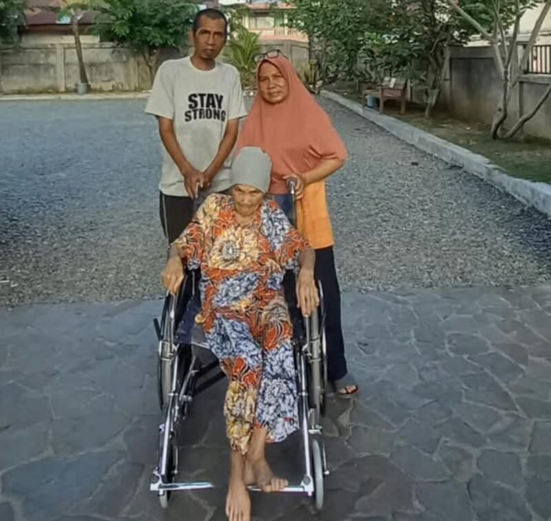 Sariana Hasibuan, lansia 76 tahun, menggunakan kursi roda bantuan Pemerintah Aceh melalui Dinas Sosial Aceh, didampingi anggota keluarga di Banda Aceh, Kamis (24/9/2026). Foto: (Dinsos Aceh).